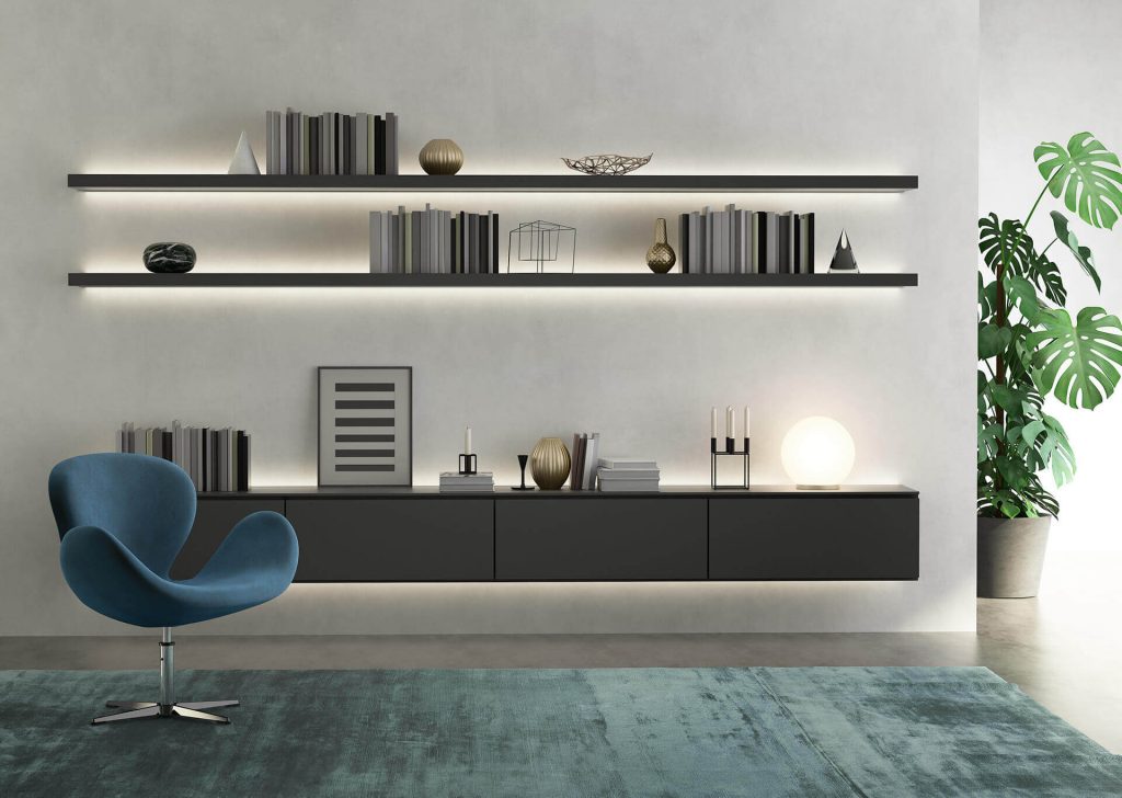 Interno contemporaneo con parete attrezzata, poltrona e illuminazione integrata.
