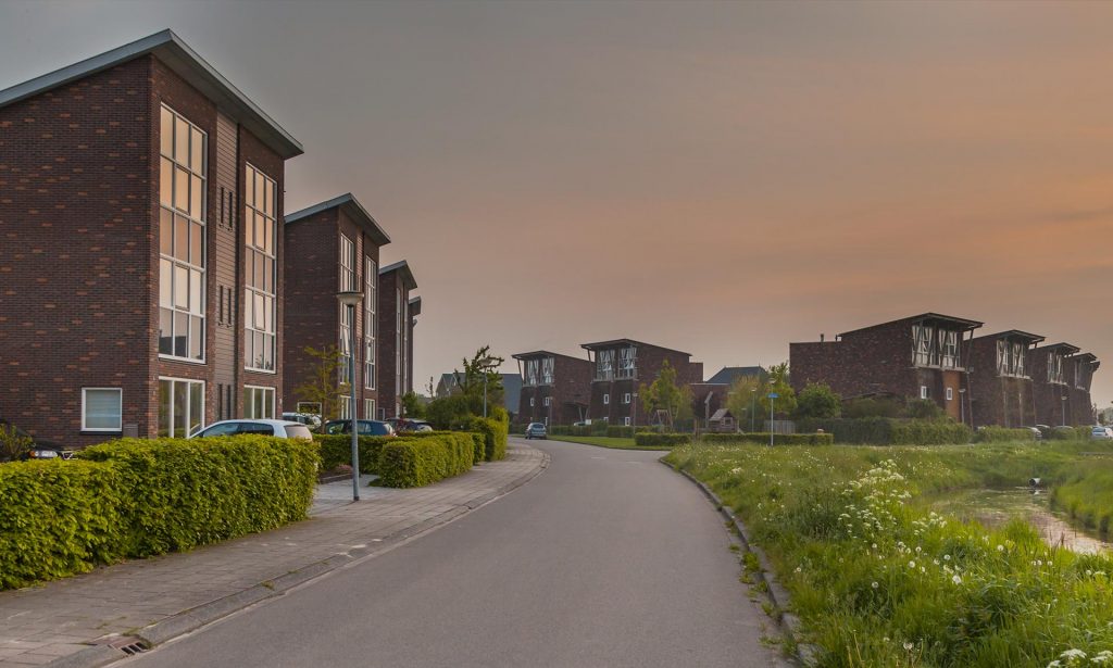 Complesso residenziale in mattoni disposto lungo una strada alberata.